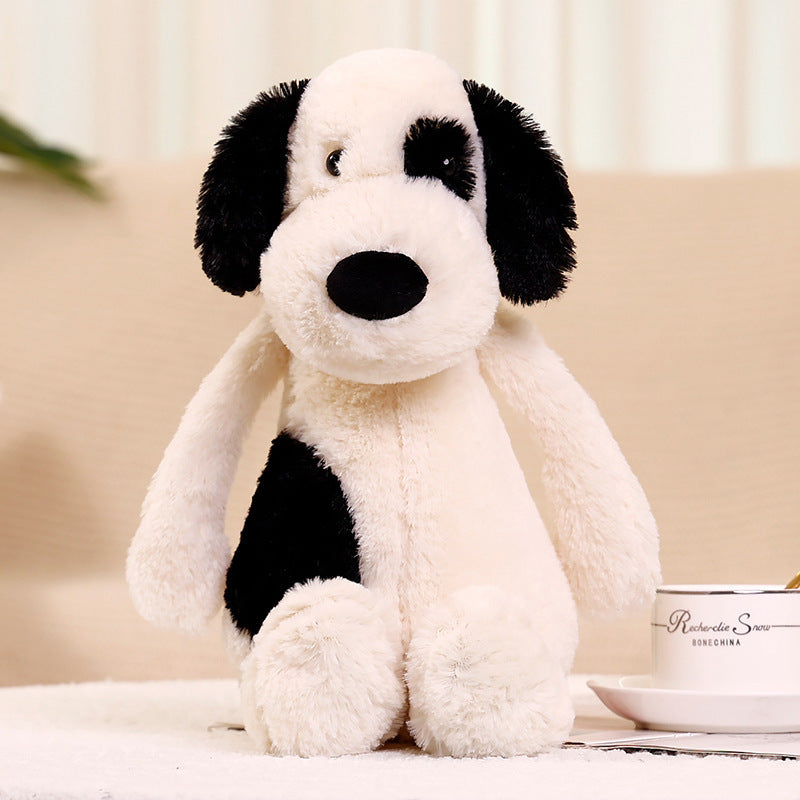 Bashful black and cream puppy plush toy front view, floppy black ears spotted stuffed dog